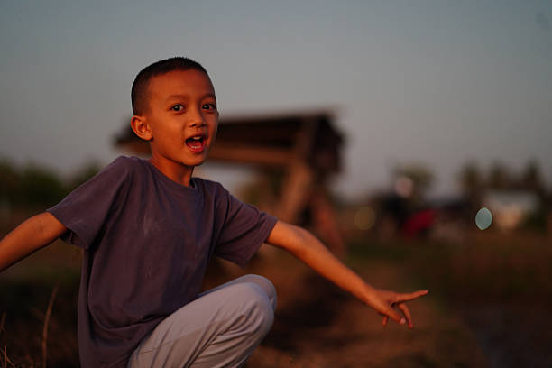 Joyful boy poses outdoors during sunset, showcasing playful expression. warm light enhances scene, creating vibrant atmosphere in natural setting