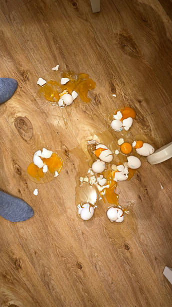 istock Broken eggs spilled on a wooden floor with shells and yolks scattered around, creating a messy accident scene and everyday kitchen mishap 2254364040