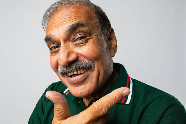 Close-up portrait of happy senior man hand on chin and smiling at camera against white background