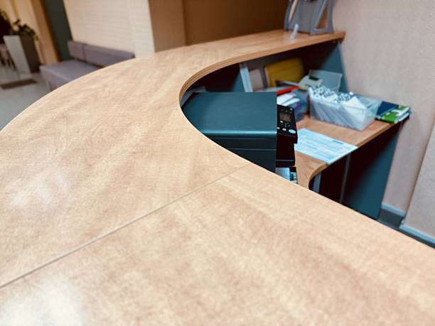 Professional Medical Reception With Tidy Workspace And Welcoming Ambiance, Efficiently Organized Clinic Reception Featuring Curved Wooden Desk And Soft Ambient Illumination