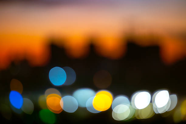 Defocused metropolitan skyline with colorful bokeh spots. Abstract urban background with bright light circles at dusk for modern website design, social media headers and artistic media.