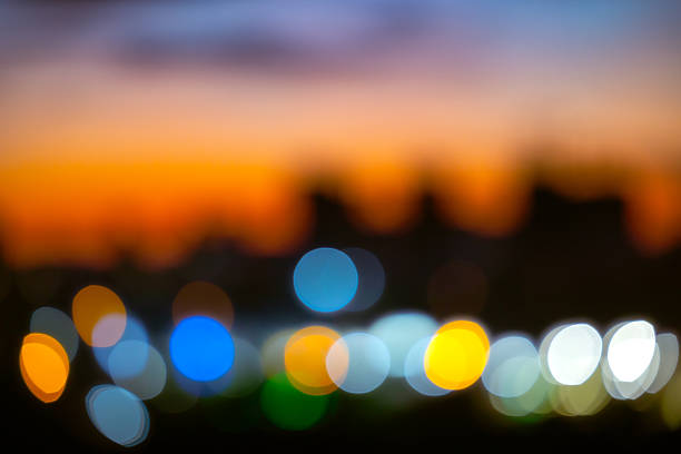 Magic night city lights bokeh for creative design. High quality defocused background with vibrant colorful circles and dark urban skyline for festive mood and professional digital art projects.