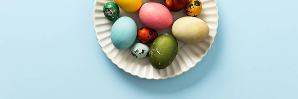 istock Beautifully decorated Easter eggs in vibrant colors are displayed on a white plate against a light blue background, symbolizing the joy of Easter festivities, banner 2254375597