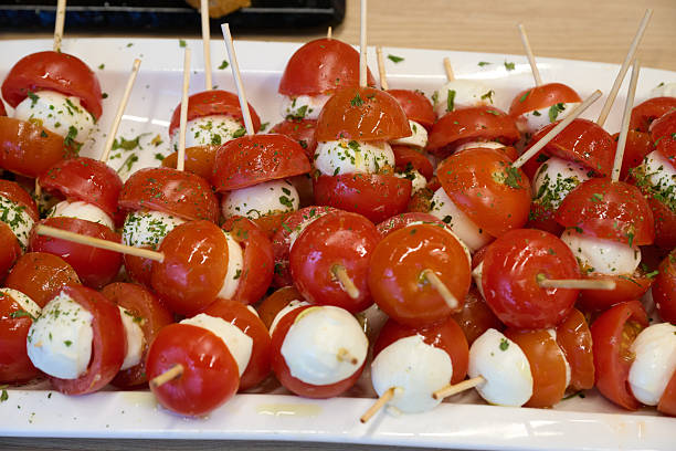 Platter filled with fresh caprese skewers, featuring cherry tomatoes, mozzarella and herbs, presented as appetizers