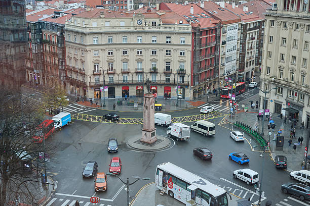 Bilbao's plaza circular showcasing a bustling intersection with cars, buses, and pedestrians moving through the urban center