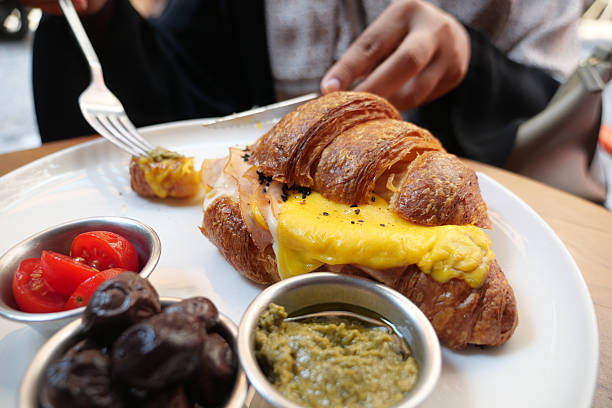 A person enjoys a croissant sandwich filled with egg and cheese.