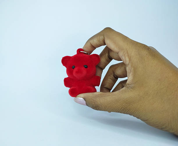 istock Hand Holding A Tiny Red Fuzzy Teddy Bear 2254384262