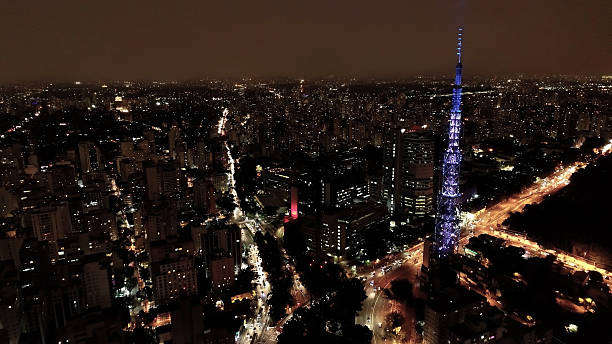 Illuminated Antenna at downtown Sao Paulo Brazil. Night metropolis landscape of landmark city. Buildings and avenues at historic center of city.
