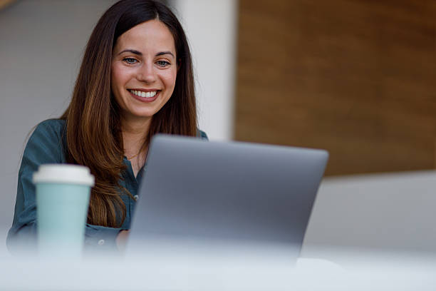 istock Professional woman smiling, working on laptop, drinking coffee in home office for remote work 2254386523