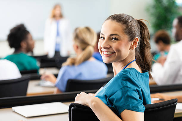 istock Smiling young woman in scrubs in a classroom setting with others present 2254387043