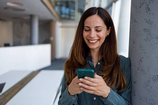 istock Professional woman smiling using phone in modern office, communicating and networking with mobile technology 2254387125
