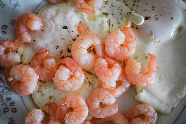 Plate with shrimp and on top of a fried egg for breakfast