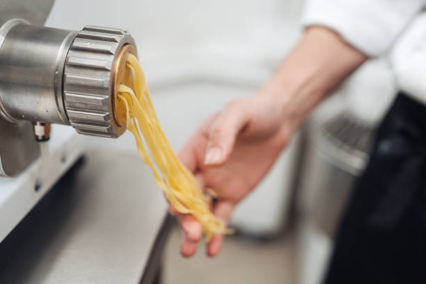 istock chef collecting fresh pasta strands from extruder into hand 2254389271