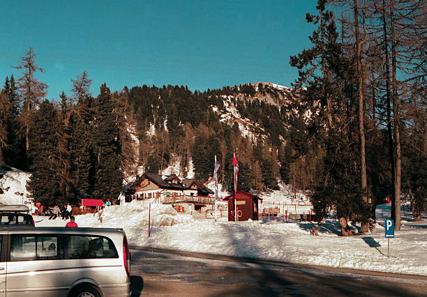Vintage scanned analog film photo of Alpine ski resort village with traditional chalets and snowy mountain backdrop with authentic film grain