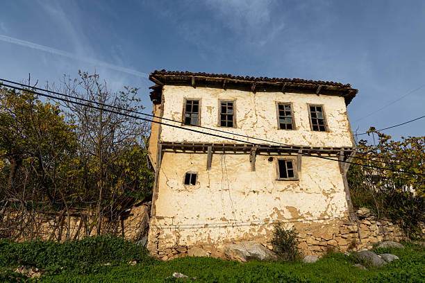 Dilapidated and neglected building with cracked walls and broken windows, signifying decay, abandonment, and the passage of time against a blue sky. Iznik, bursa, turkey