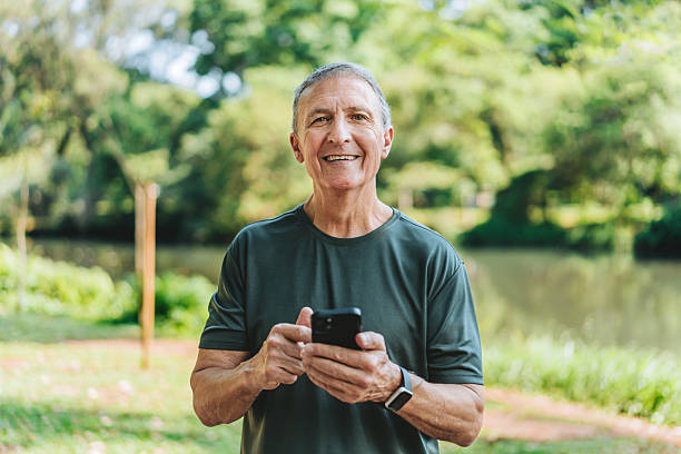 istock Elderly man using a smartphone in a public park looking at the cmaera 2254391993