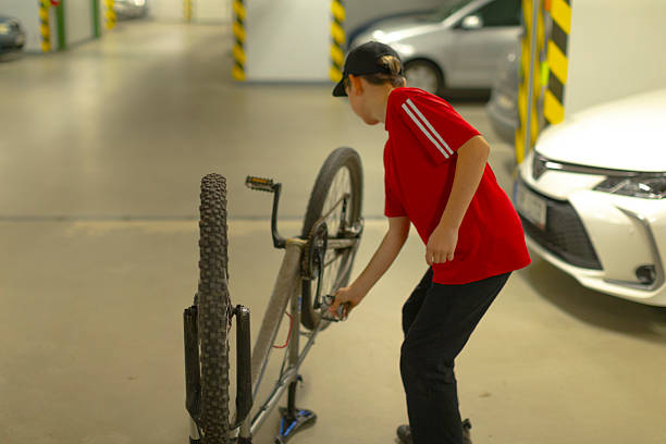 istock Adolescent lifting bicycle onto repair rack in parking garage setting 2254392314