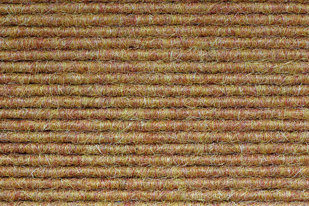 You see a close up of a carpet floor with ribbed texture in yellow brownish color