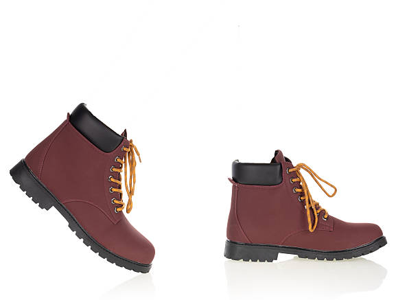 Pair of stylish burgundy outdoor boots with black ankle collar and yellow laces isolated on a white background