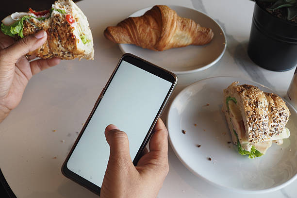 istock Hands holding sandwich and phone in a cafe setting 2254397537