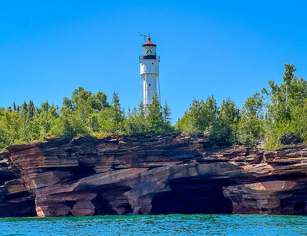 Devils Island Lighthouse located on one of the Apostle Islands, on Lake Superior in Ashland County, Wisconsin. Set behind the sandstone sea cliff with caves and surrounded by vegetation.