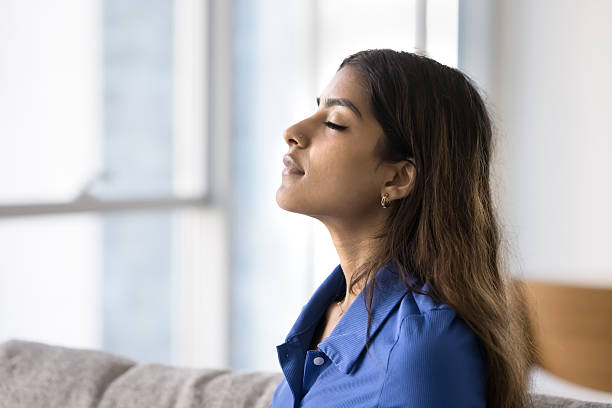 istock Young 20s Indian woman sitting on sofa with eyes closed 2254399528
