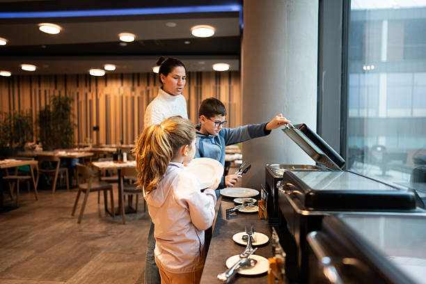 istock Family At Buffet: Mother With Children Serves Themselves In A Modern Restaurant 2254400560