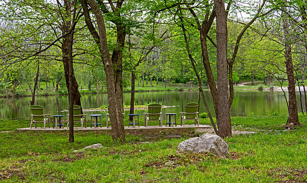 Green lawn chairs facing still waters provide an opportunity for relaxing moments in nature in beautiful green surroundings.