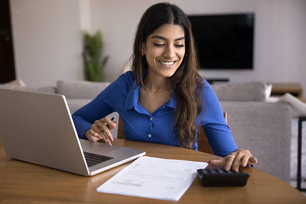 istock Woman sit at table with laptop, calculator, and paperwork 2254402844