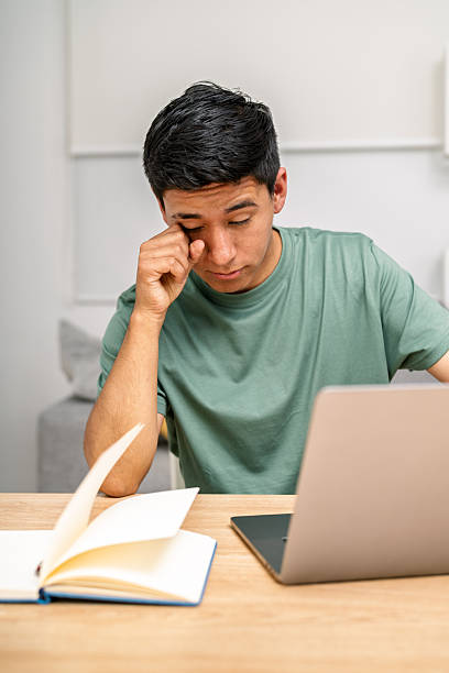 istock Tired young man working from home rubbing eye 2254404531