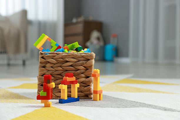 Construction toy. Figures made with building bricks and wicker basket of blocks on floor indoors, space for text