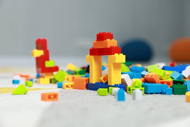 Construction toy. Figures made with building bricks and colorful blocks on floor indoors, closeup