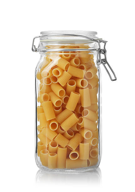 Glass jar with raw rigatoni pasta isolated on white