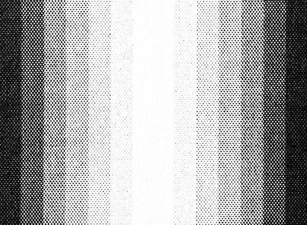 Macro close-up of black halftone dots printed on white paper, forming dark vertical side bands that fade inward toward a bright blank center strip, with visible raster screening and grain.