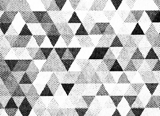 Macro close-up of black halftone dots on white paper forming a dense geometric mosaic of triangles and diamond shapes, with varied dot density, sharp edges, and visible print grain.