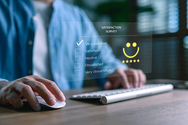 istock Customer satisfaction survey and feedback evaluation concept. Man completing online rating form with smiley face icon and five-star review for digital experience, service quality, and user insights. 2254409570
