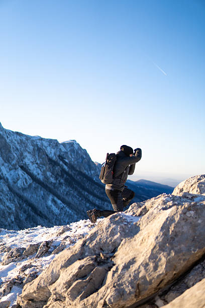 Man taking a photo on the mountain peak covered with snow