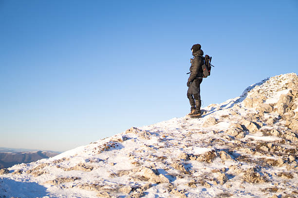 Man standing on the rocky mountain peak covered with snow