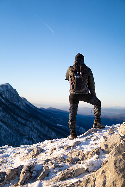 istock Man standing on the mountain peak with mountain range in the back. 2254409835
