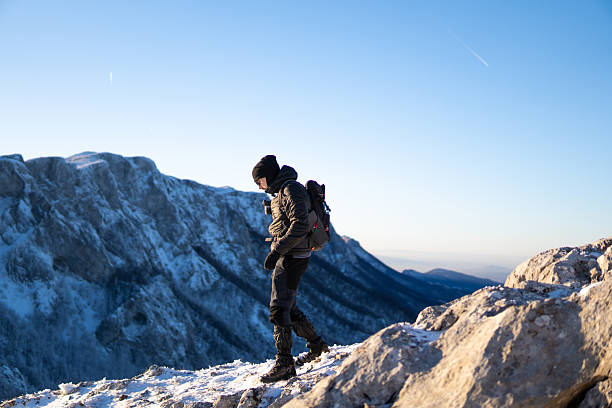 istock Man walking down the snow field with mountain range in the back. 2254409852