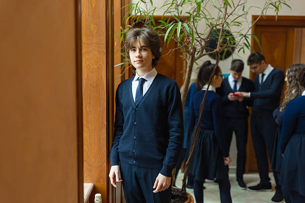 A group of well-dressed students in school uniforms gathered in a classroom, with a focus on a young student standing near the front