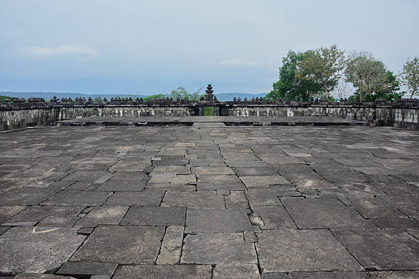 A wide-angle view of the textured grey stone pavement and perimeter walls at the Ratu Boko archaeological park, showing the scale of the ancient Javanese ruins
