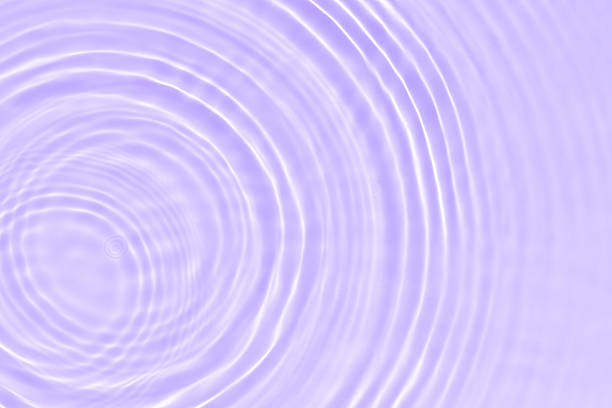 Purple water bubbles on the surface ripples. Defocus blurred transparent pink colored clear calm water surface texture with splash and bubbles. Water waves with shining pattern texture background