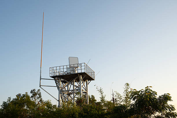 The Sandiaojiao Lighthouse stands prominently beside a radar station against a backdrop of moody skies and lush greenery.
