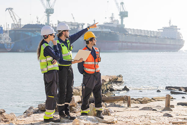 istock Workers discuss plans at a port with a cargo ship in the background 2254438923