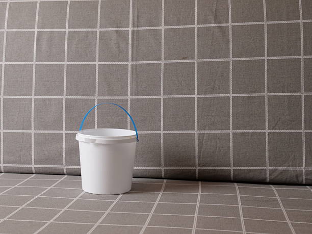 White plastic bucket with handle on sofa with checkered upholstery in minimalist scene.