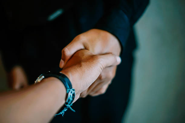 A close-up shows two individuals shaking hands, symbolizing agreement, partnership, and successful collaboration. This professional gesture represents trust and a new beginning in business dealings.