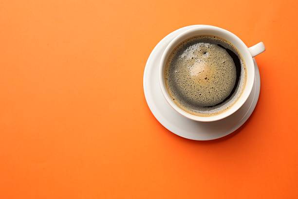 istock Fresh coffee in cup on orange background, top view. Space for text 2254444402