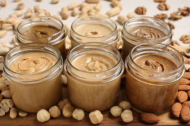 istock Many tasty nut butters in jars and nuts on table, closeup 2254445572
