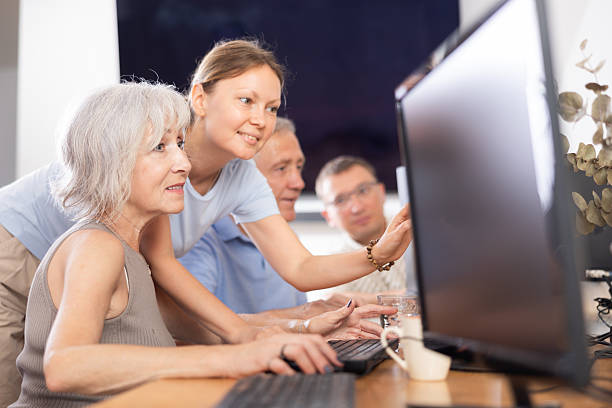 istock Female teacher helps an elderly woman learn how to use computer in nursing home 2254446148